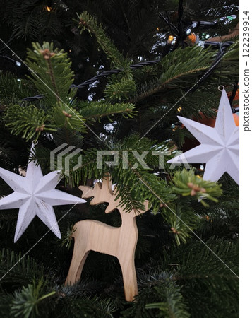 Wooden reindeer and white stars hanging on christmas tree in prague zoo Wooden reindeer and white stars hanging on christmas tree in prague zoo 122239914