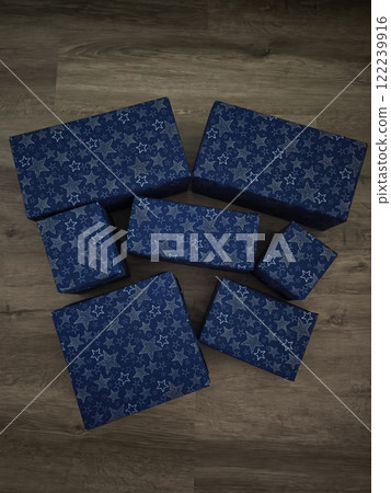 Christmas presents wrapped in blue paper with white stars resting on wooden floor Gift boxes New Year preparation decor 122239916