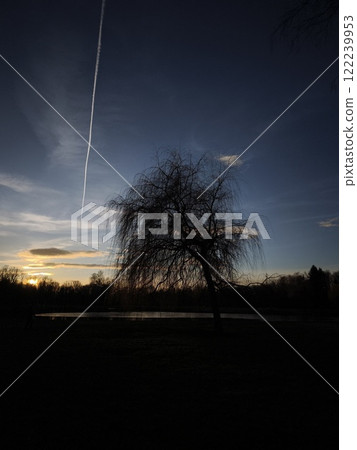Airplane leaving contrail over a Bagr lake at sunset in Stromovka ceske budejovice, czechia Airplane leaving contrail over a Bagr lake at sunset in Stromovka ceske budejovice, czechia 122239953