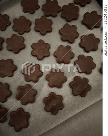 Chocolate flower shaped cookies baking on parchment paper in prague christmas time 122240015