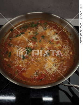Delicious tomato sauce simmering with grated cheese and herbs in a pan 122240041