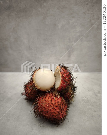 Fresh rambutan fruit showing white flesh on grey background Fresh rambutan fruit showing white flesh on grey background 122240120