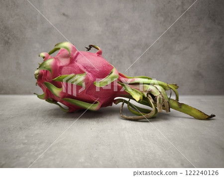 Fresh vibrant dragon fruit resting on gray surface Fresh vibrant dragon fruit resting on gray surface 122240126