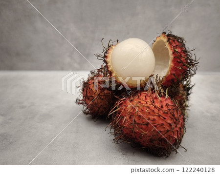 Fresh rambutan fruit showing white flesh on grey table Fresh rambutan fruit showing white flesh on grey table 122240128