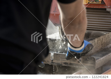 Rear view of a person using a circular saw or angle grinder 122241824