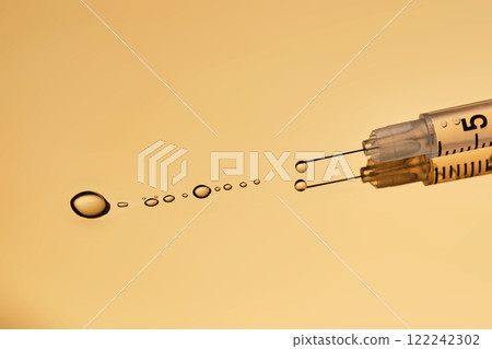 A drop of gel pours from a syringe for cosmetic procedures. 122242302