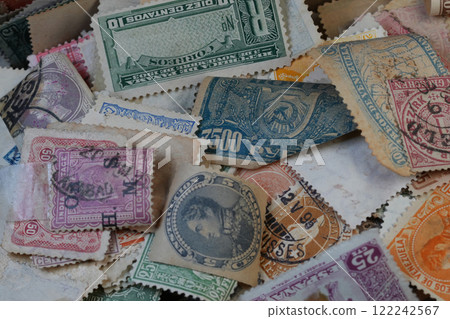 Closeup on a scattered collection of a variety of international used Vintage Postage Stamps 122242567
