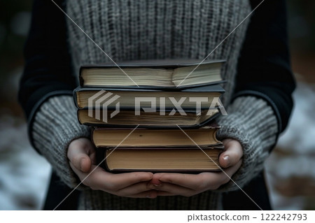 A girl on the street holds a stack of books in front of her 122242793