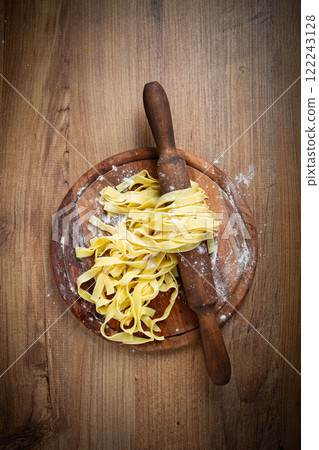 raw tagliatelle pasta, homemade, on a rolling pin, top view, on a cutting board, cooking concept, raw tagliatelle pasta, homemade, on a rolling pin, top view, on a cutting board, cooking concept, 122243128