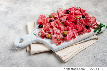 Assorted, meat appetizer, prosciutto, salami and ham, with olives , on a wooden white board, light background, breakfast, top view, close-up, no people 122243133