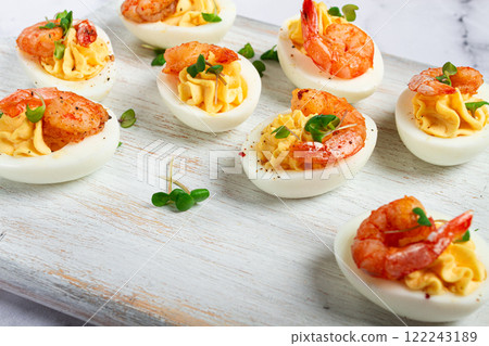 Boiled eggs stuffed with yolk and seasoned with mayonnaise, stuffed eggs with shrimp, on a white wooden chopping board, selective focus, close-up, without people, 122243189