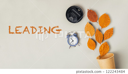 A clock and leaves are on a wall with the word Leading written below them A clock and leaves are on a wall with the word Leading written below them 122243484
