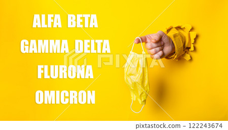 Yellow background with a hand holding a mask 122243674