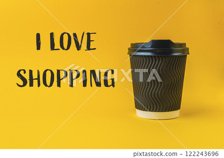Coffee cup with a black lid sits on a yellow background Coffee cup with a black lid sits on a yellow background 122243696