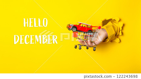 Hand holding a toy car in front of a yellow background 122243698