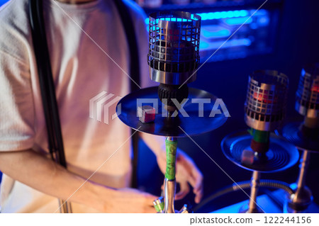 Close up of a hookah made of metal and glass on a wooden table 122244156