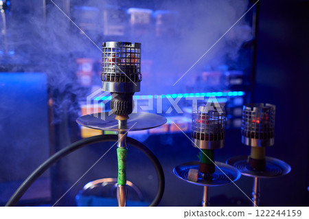 Close up of a hookah made of metal and glass on a wooden table 122244159