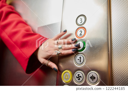 Pressing the elevator button in contemporary high rise buildings signifies modern urban convenience Pressing the elevator button in contemporary high rise buildings signifies modern urban convenience 122244185
