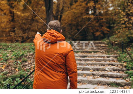 Blonde male pointing finger outdoors, he hiking on woodland, rear view. Active lifestyle concept. Trip, travel and people banner. High quality photo 122244584