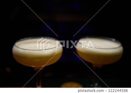 Elegant and Stunning Cocktail Glasses Clinking Together in a Softly Dimly Lit Bar Setting Elegant and Stunning Cocktail Glasses Clinking Together in a Softly Dimly Lit Bar Setting 122244586