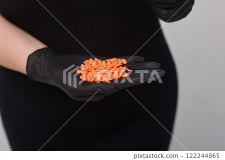 Hand Holding Bright Orange Pills in a Medical Setting Indicating Health and Wellness Hand Holding Bright Orange Pills in a Medical Setting Indicating Health and Wellness 122244865