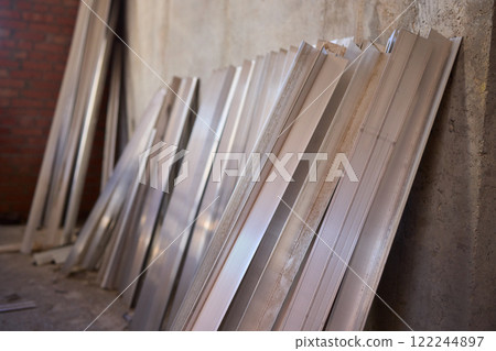A variety of metal sheets are carefully stacked in a spacious construction area for use A variety of metal sheets are carefully stacked in a spacious construction area for use 122244897