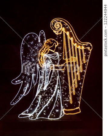 Illuminated Angel Playing a Harp Decoration Against a Dark Background Illuminated Angel Playing a Harp Decoration Against a Dark Background 122244944