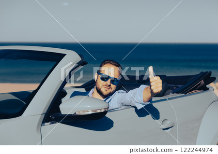 Successful young businessman on a beach. Man sitting in the cabriolet classic car. Successful young businessman on a beach. Man sitting in the cabriolet classic car. 122244974