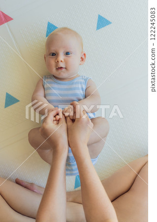 A mother practices baby gymnastics with her 3-month-old on a soft children's play mat. A joyful and nurturing moment focused on bonding, development, and care. Early childhood, fitness, and parenting A mother practices baby gymnastics with her 3-month-old on a soft children's play mat. A joyful and nurturing moment focused on bonding, development, and care. Early childhood, fitness, and parenting 122245083