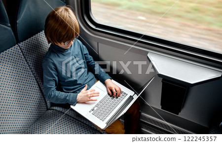Young Boy Using Laptop on Train Seat. 122245357