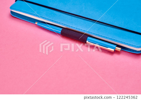 Blue Notebook with Pen on Vibrant Pink Background. Blue Notebook with Pen on Vibrant Pink Background. 122245362