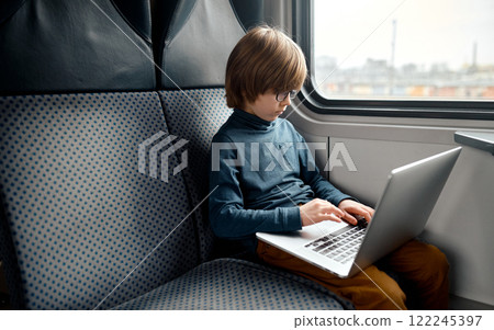 Young Boy Engaged with Laptop During Train Ride. Young Boy Engaged with Laptop During Train Ride. 122245397
