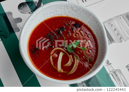 Vibrant Tomato Soup Garnished with Herbs and Oil Drizzle. 122245441