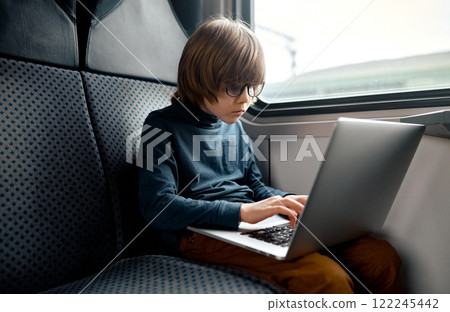 Focused Boy Typing on Laptop in Train. Focused Boy Typing on Laptop in Train. 122245442
