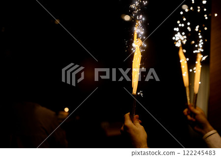 Hands Holding Sparkling Fireworks in Darkness. Hands Holding Sparkling Fireworks in Darkness. 122245483
