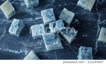 Cubes of blue cheese stacked on a dark marble surface. 122245607