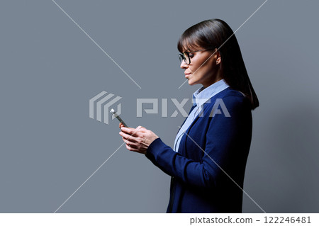 Profile view mature woman using smartphone on grey background Profile view mature woman using smartphone on grey background 122246481