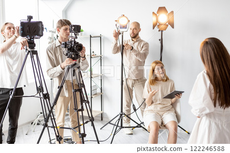 Behind scene. Producer team. Studio workers prepare equipment filming. Female art director explains video shoot concept to models. 122246588