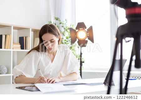 Studio script. Media document. Business woman writing paper taking notes in bright photo studio workplace. Girl manager author studies works plans desk. Studio script. Media document. Business woman writing paper taking notes in bright photo studio workplace. Girl manager author studies works plans desk. 122246612