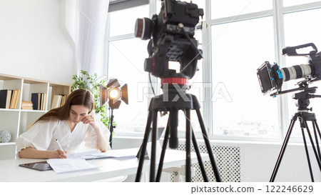 Script sign. Vlog studio. Woman writing near professional cameras spotlights. Media recording project work technical task. 122246629