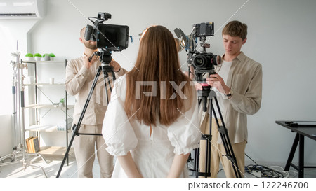 Shooting model. Backstage studio. Girl with loose hair stands front of cameras. Woman poses photo video filming interview production. Shooting model. Backstage studio. Girl with loose hair stands front of cameras. Woman poses photo video filming interview production. 122246700