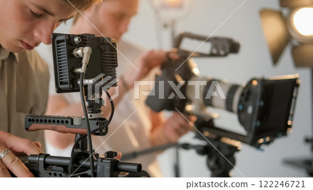 Cameraman backstage. Videographer team. Group of men work professional filming equipment floodlit studio. Crew preparing shooting. 122246721