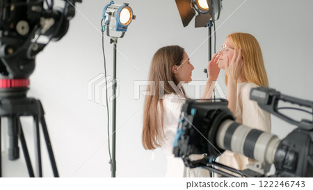Preparation model. Work stylist photo. Brunette corrects hair blonde girl before filming. Women getting ready scene photo professional studio. Preparation model. Work stylist photo. Brunette corrects hair blonde girl before filming. Women getting ready scene photo professional studio. 122246743
