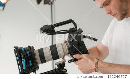 Videographer work. Cameraman set. Man looks display professional filming equipment. Photographer adjusts studio production equipment. 122246757