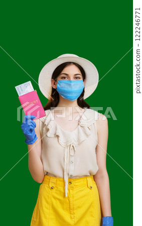 Confident tourist woman in face mask protective gloves holding pink passport with tickets isolated on green copy space background. Confident tourist woman in face mask protective gloves holding pink passport with tickets isolated on green copy space background. 122246771