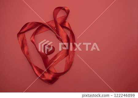 red voluminous heart with red satin ribbon on red background, concept of love celebration 122246899
