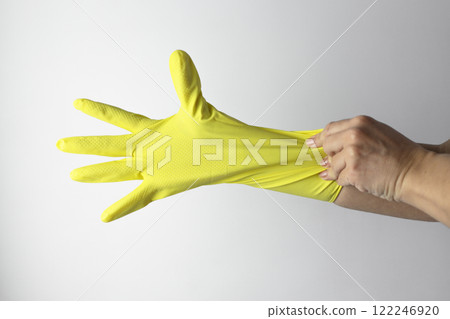 Cleaning concept. A hand puts a yellow cleaning glove on the other hand 122246920