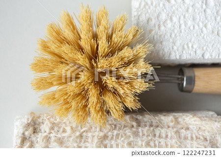 Wooden tableware brush with bamboo fibers and kitchen cellulose sponge close-up. Eco-friendly lifestyle concept Wooden tableware brush with bamboo fibers and kitchen cellulose sponge close-up. Eco-friendly lifestyle concept 122247231