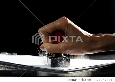 Against their will, hand delivers stamp, marking contract with forced approval. Ink signs though carrying authority, lack genuine force. Office air is thick with tension as document is pushed through Against their will, hand delivers stamp, marking contract with forced approval. Ink signs though carrying authority, lack genuine force. Office air is thick with tension as document is pushed through 122247445