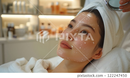 A woman with a towel around her head getting facial treatment at the spa A woman with a towel around her head getting facial treatment at the spa 122247450